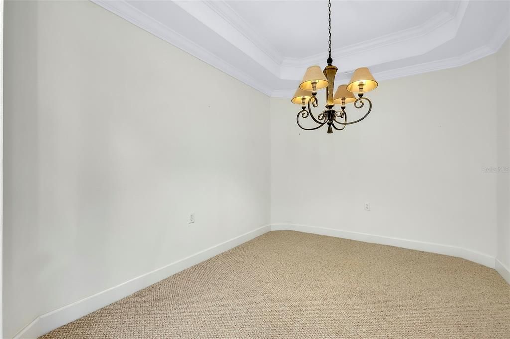 Dining Room featuring an inviting chandelier, carpet, a tray ceiling, and ornamental molding