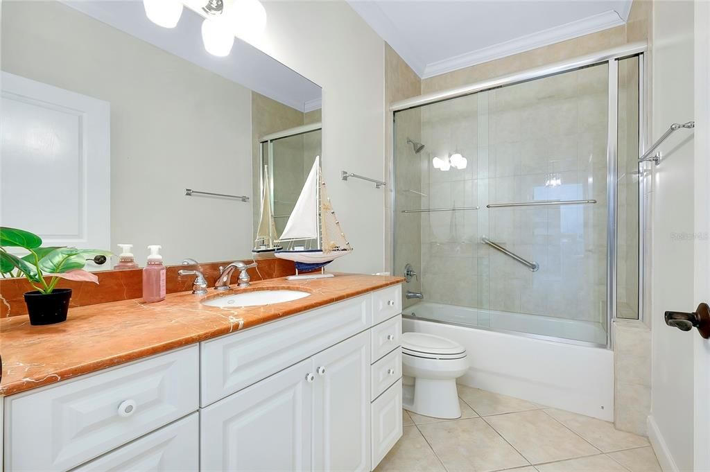 Full bathroom with vanity, combined bath / shower with glass door, tile patterned floors, crown molding, and toilet