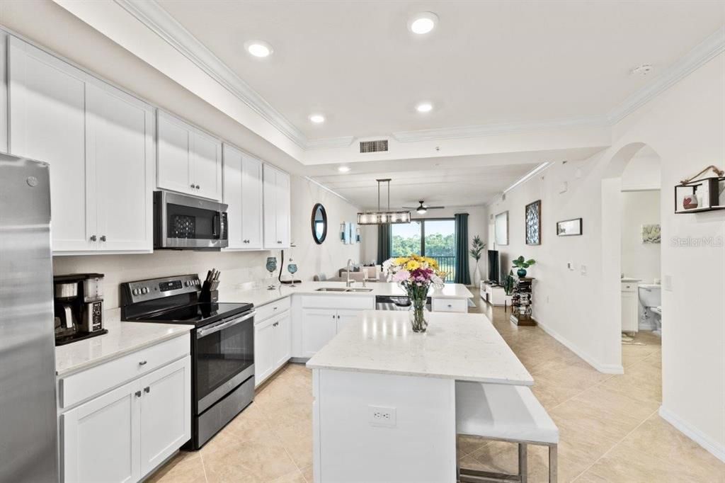 Gourmet kitchen featuring quartz countertops, stainless steel appliances, wood shaker cabinets, a breakfast bar, and island.