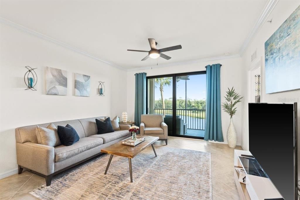 Living room featuring 16" tile, high ceilings, crown molding, and sliding glass doors leading to the covered screened-in patio.