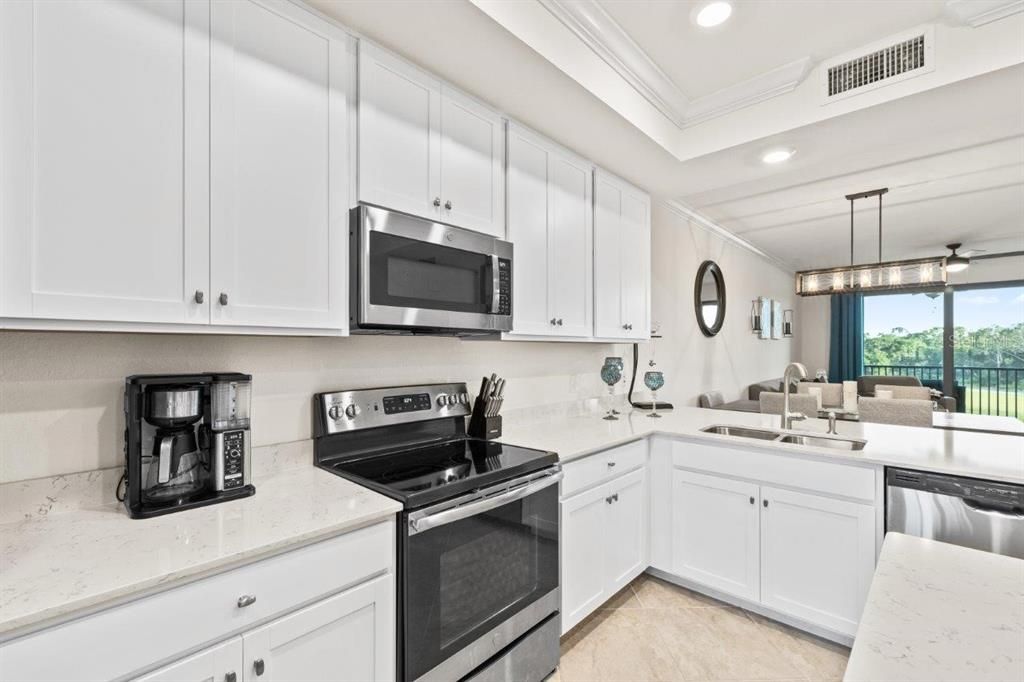 Gourmet kitchen featuring quartz countertops, stainless steel appliances, wood shaker cabinets, a breakfast bar, and island.