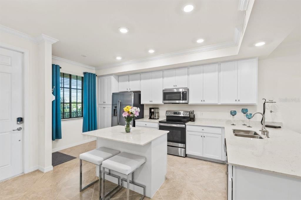 Gourmet kitchen featuring quartz countertops, stainless steel appliances, wood shaker cabinets, a breakfast bar, and island.