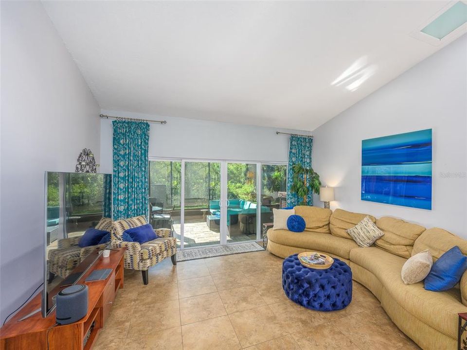 Spacious and bright living area with vaulted ceilings and large sliding glass doors that offer natural light and seamless access to the outdoor patio. The open layout maximizes flow between indoor and outdoor spaces, perfect for entertaining or relaxing.