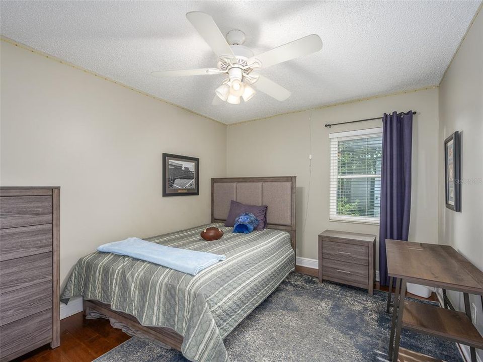 This cozy bedroom is perfect for a guest room or children's room, featuring natural light from a large window and neutral tones. The space offers versatility and charm, with hardwood floors that are easy to customize to suit personal style.