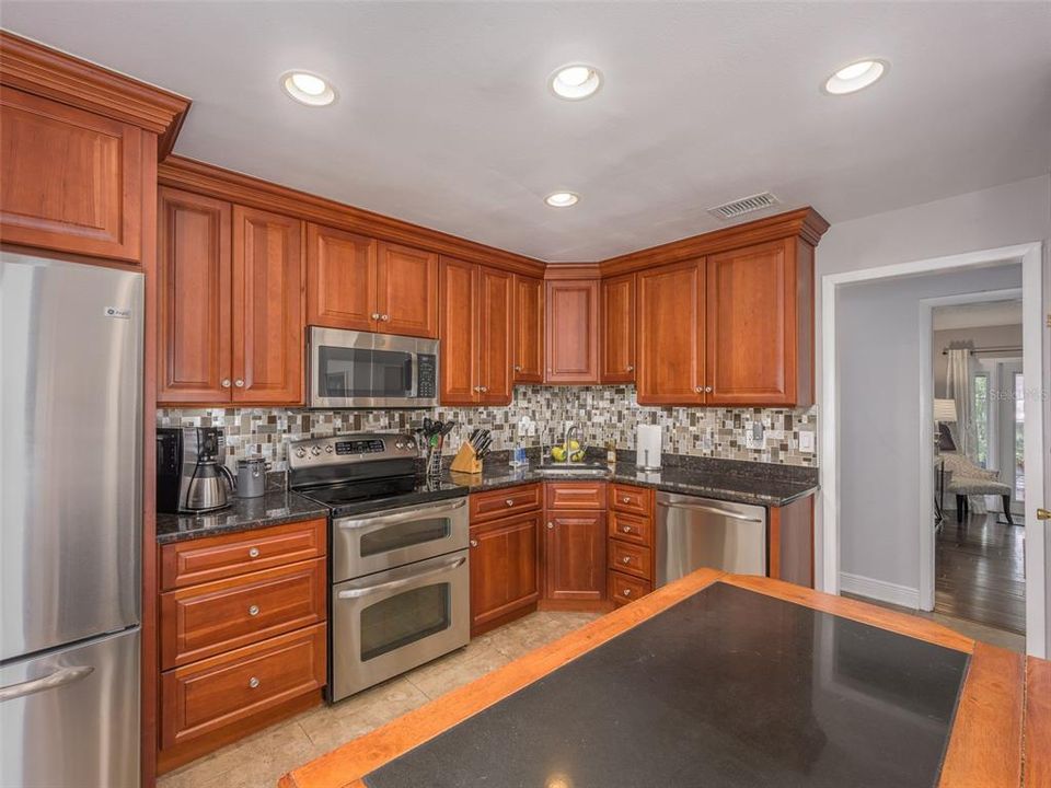 Spacious and well-lit kitchen with rich wood cabinetry, stainless steel appliances, and modern tile backsplash. Ample counter space and storage, perfect for cooking and entertaining. The open layout connects seamlessly to the rest of the home.