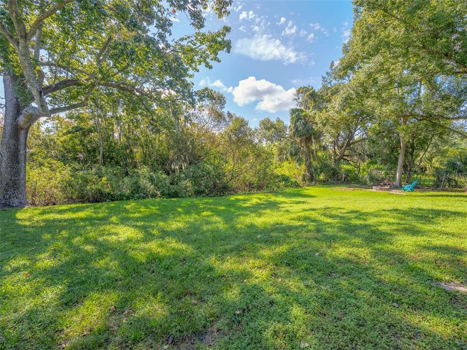 This peaceful backyard offers a spacious lawn shaded by mature trees, perfect for relaxing or outdoor activities. The lush greenery and tranquil setting provide a private, natural retreat for guests. Ideal for enjoying sunny afternoons or quiet evenings.