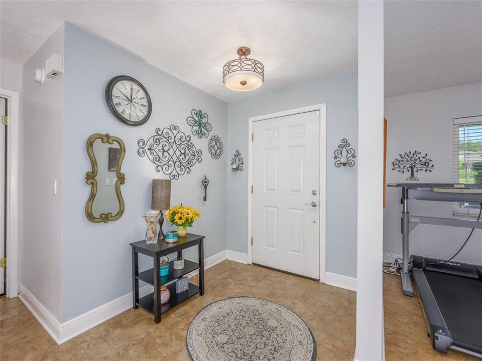 Bright and welcoming entryway with neutral tones and elegant tile flooring. The entry provides a warm first impression, featuring ample wall space for personalization and easy access to the rest of the home. A well-lit space ideal for greeting guests.