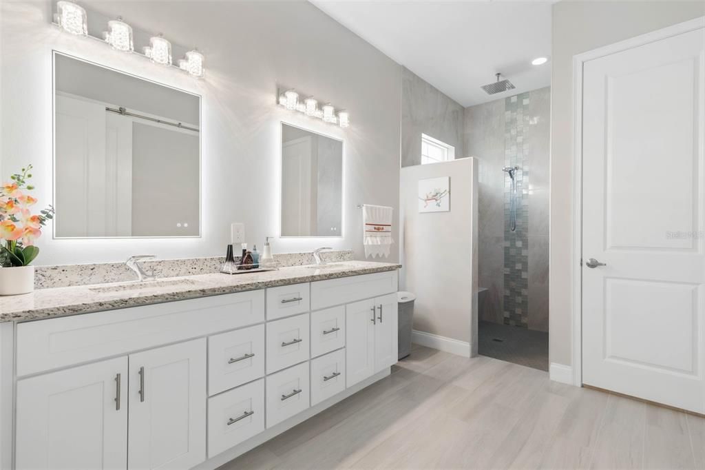 Primary bathroom with double sinks and backlit LED mirrors