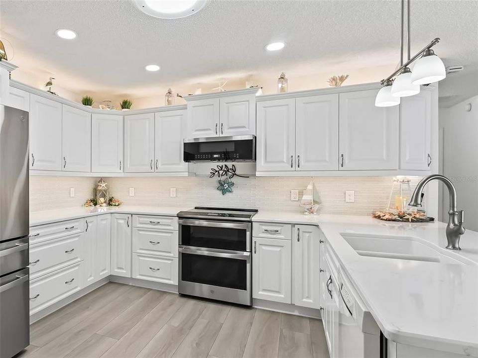 Quartz Counters, Soft Closure Cabinets with Pull Out Shelving, Glass Backsplash and Crown Molding Over Cabinets