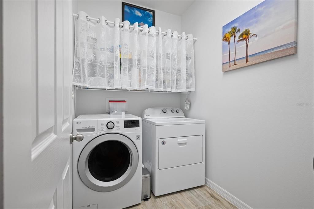 The washroom is equipped with a washer and dryer, conveniently situated between the garage and kitchen for easy access."