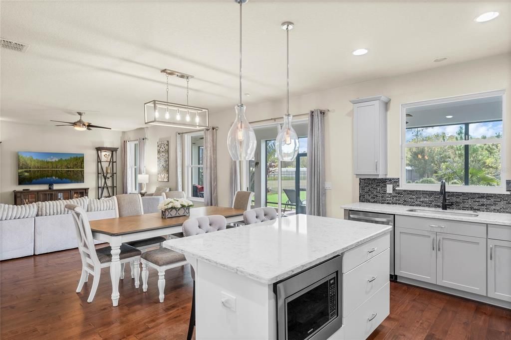 The kitchen looks out onto a casual dining space and spacious family room with sliding glass door access to a huge SCREENED LANAI and the expansive backyard beyond.