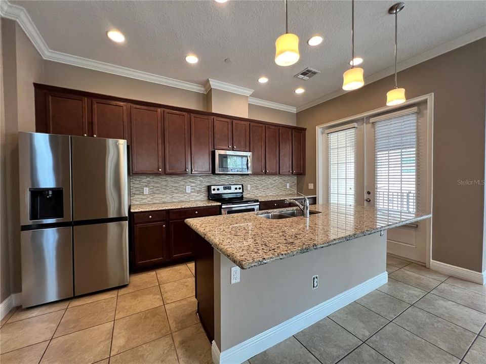 kitchen features granite countertop, stylish tile backsplash