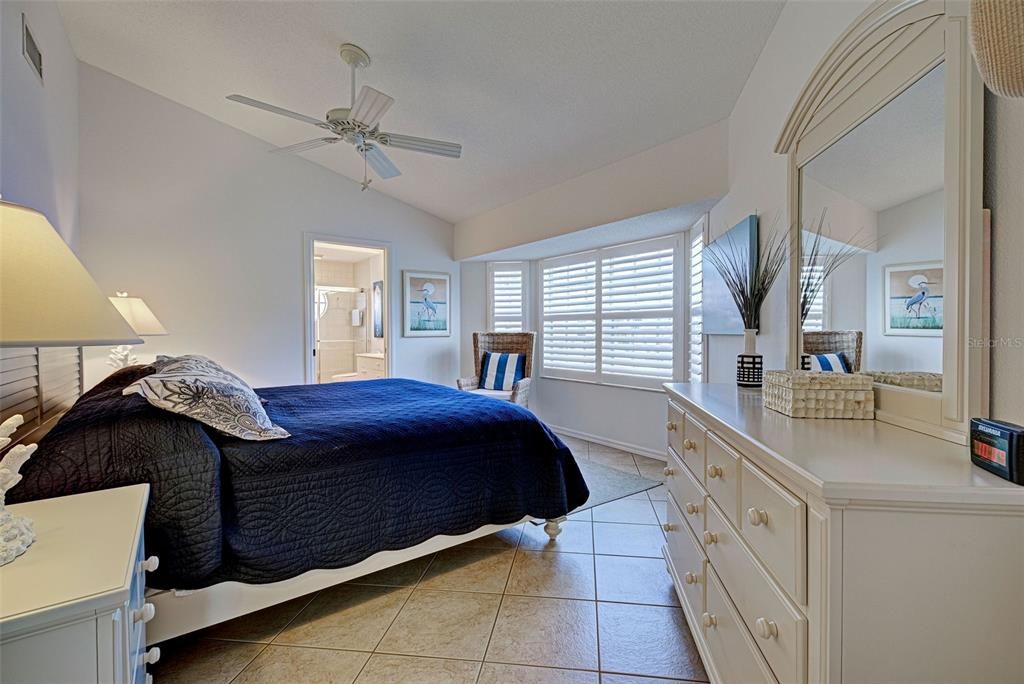 Sumptuous primary suite has cathedral ceilings, plantation shutters and an ensuite bathroom.