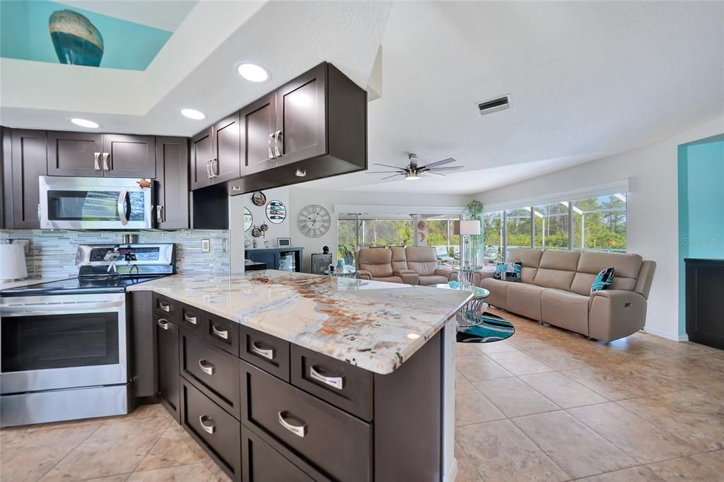 Beautiful counters and cabinets with views overlooking living room to pool