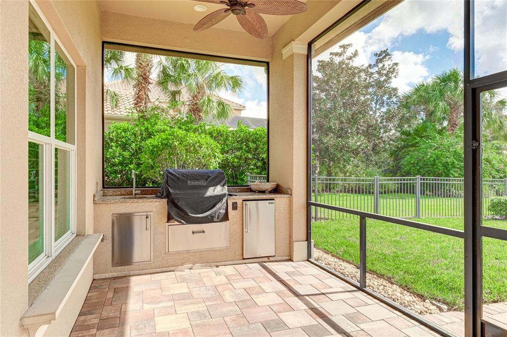 Outdoor kitchen includes a sink, grill and fridge