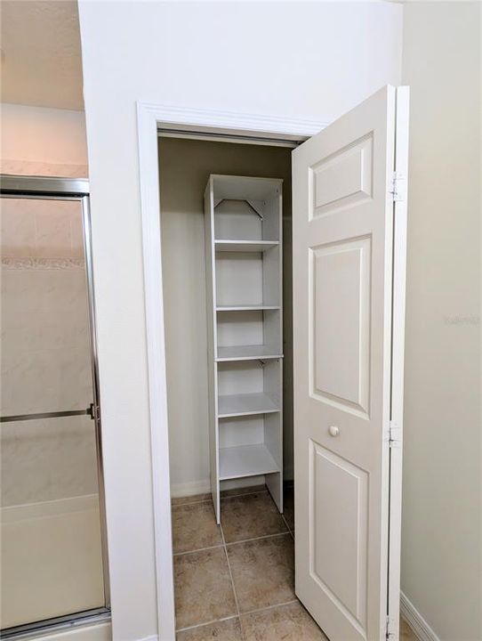 Primary linen closet with built-in shelves