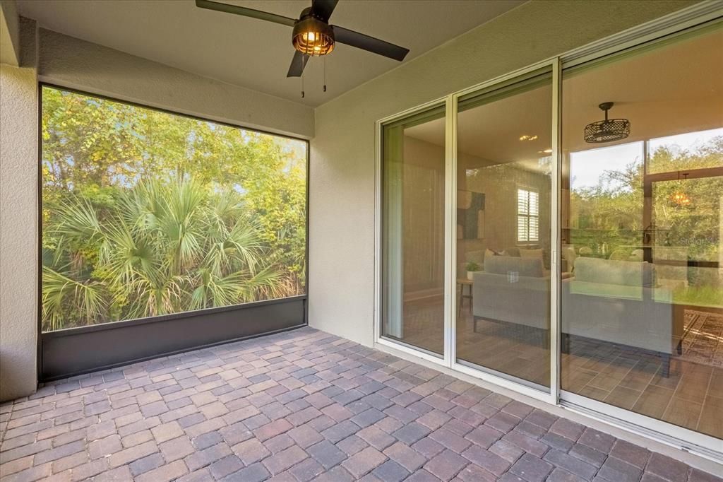 TRIPLE SLIDING GLASS DOORS off the spacious living area frame the wooded CONSERVATION VIEWS and open up to SCREENED LANAI overlooking a lush backyard.