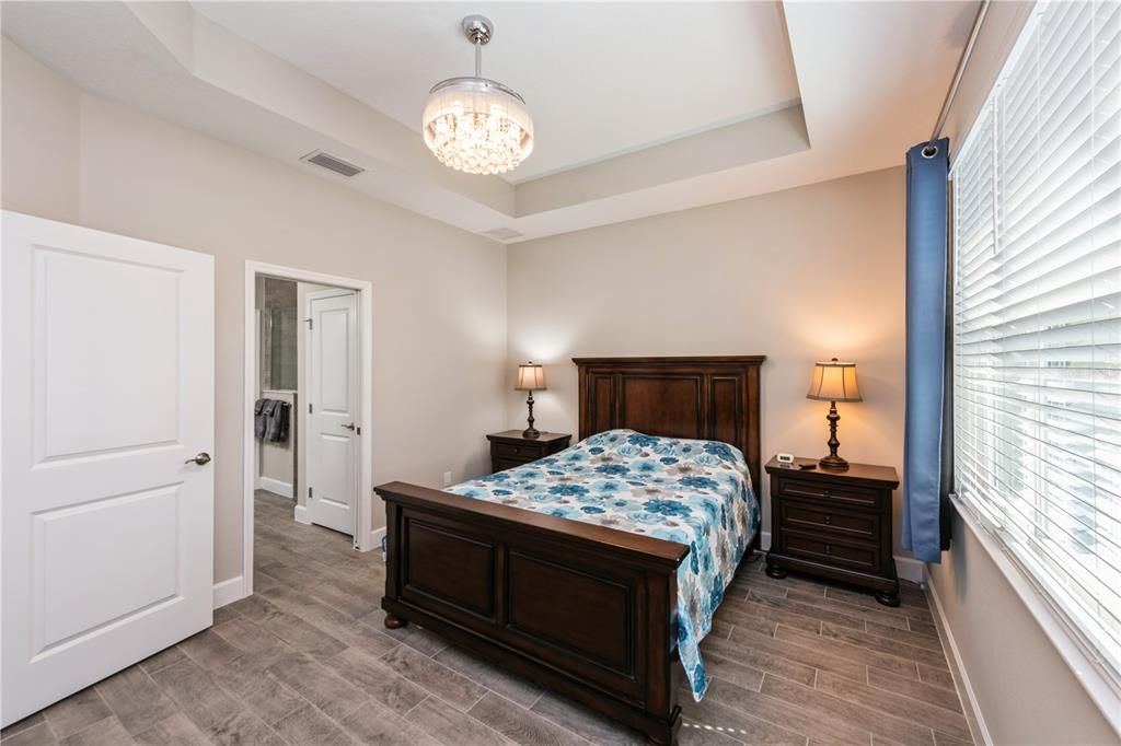 Elegant primary suite with tray ceiling and views of the pond.