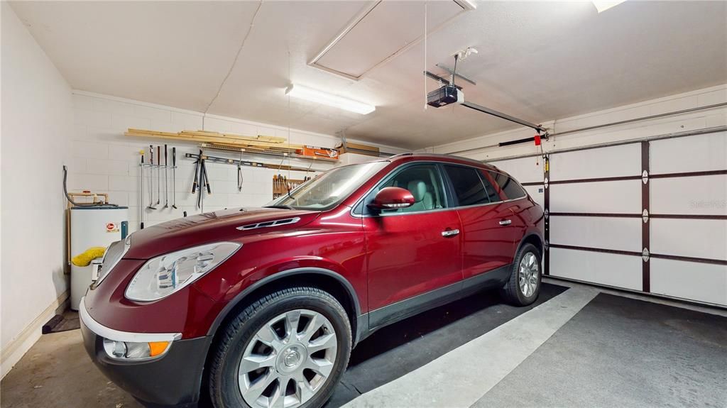 The two car garage. A workbench and cabinets on the other side of the vehicle. Vehicle does not convey