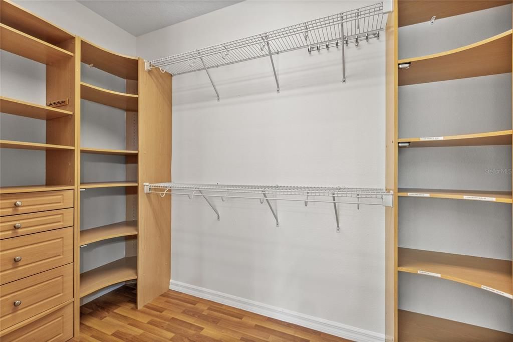 Primary bedroom walk in closet with custom built ins