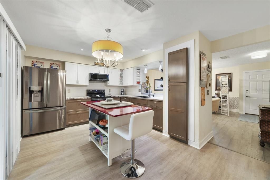 The modern kitchen delivers stylish two-tone cabinetry, STAINLESS STEEL APPLIANCES and French doors open to a SCREENED LANAI and the backyard/green space beyond.