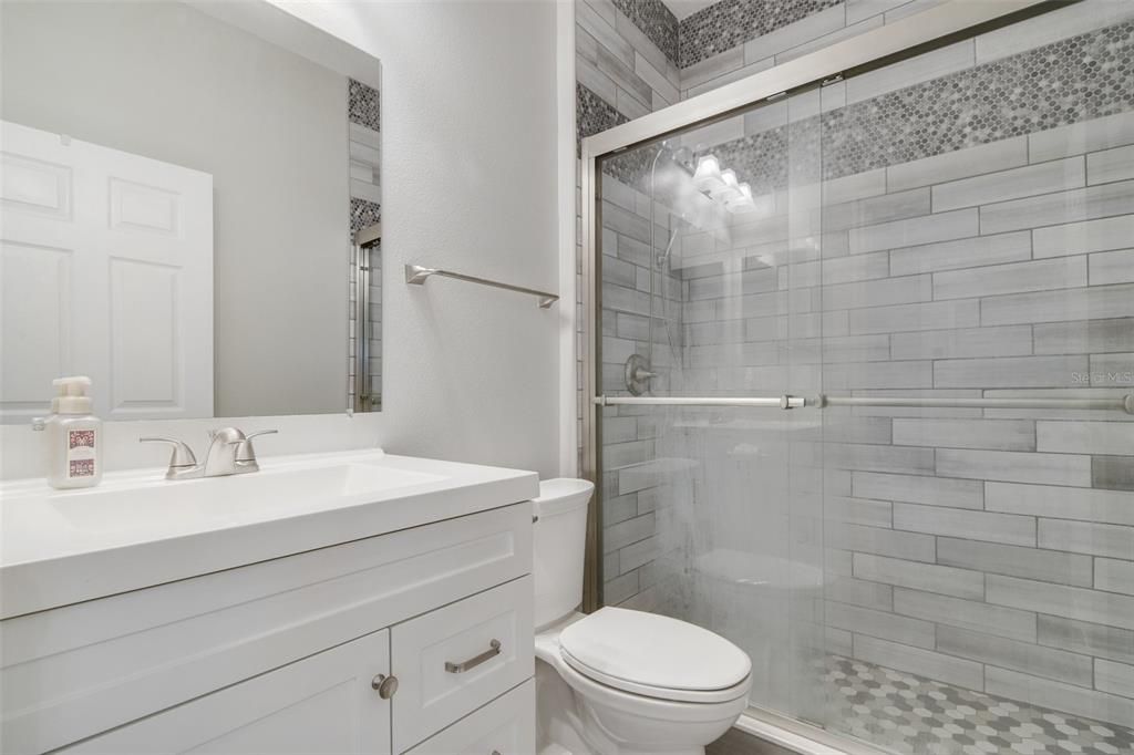 Bedrooms two and three share an UPDATED FULL GUEST BATH featuring a custom tiled walk-in shower.