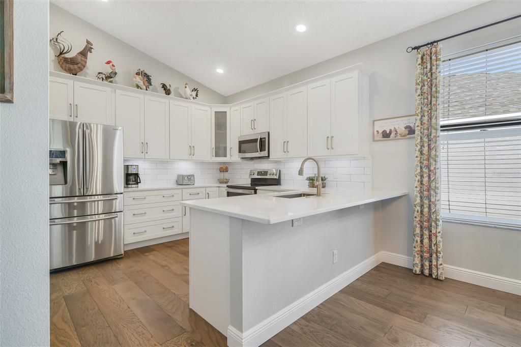 The gorgeous kitchen is next, remodeled in 2024, the home chef will delight in the 42” SHAKER STYLE CABINETRY, stylish bronze hardware, STAINLESS STEEL APPLIANCES, tiled backsplash, QUARTZ COUNTERTOPS and there is a pantry for all your storage needs.