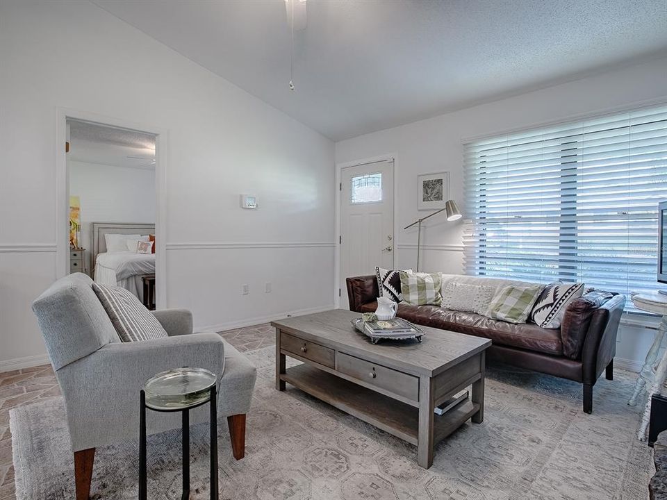 The living room window overlooks the covered front porch and lets natural light into the home ~