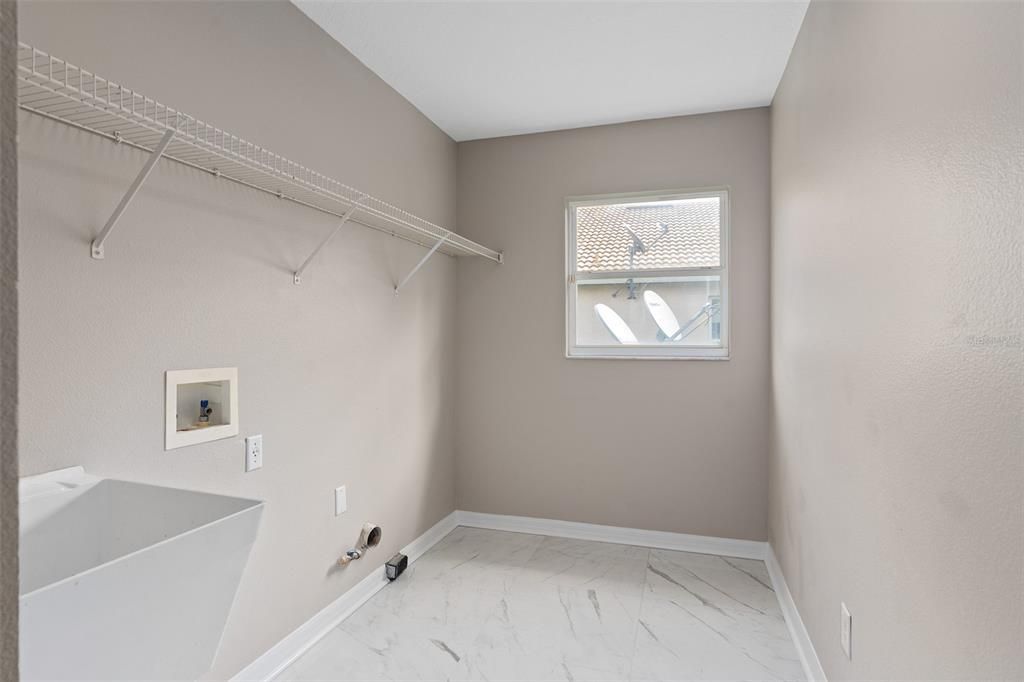 LAUNDRY ROOM DONE IN 24 INCH PORCELAIN TILE WITH SINK. DRYER ALSO HAS AVAILABILITY FOR A GAS HOOKUP.