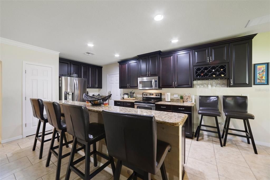 The beautiful kitchen was designed with the home chef in mind offering STAINLESS STEEL APPLIANCES, granite countertops, rich espresso cabinets, wine storage, WALK-IN PANTRY and there is additional breakfast bar seating on the large ISLAND.