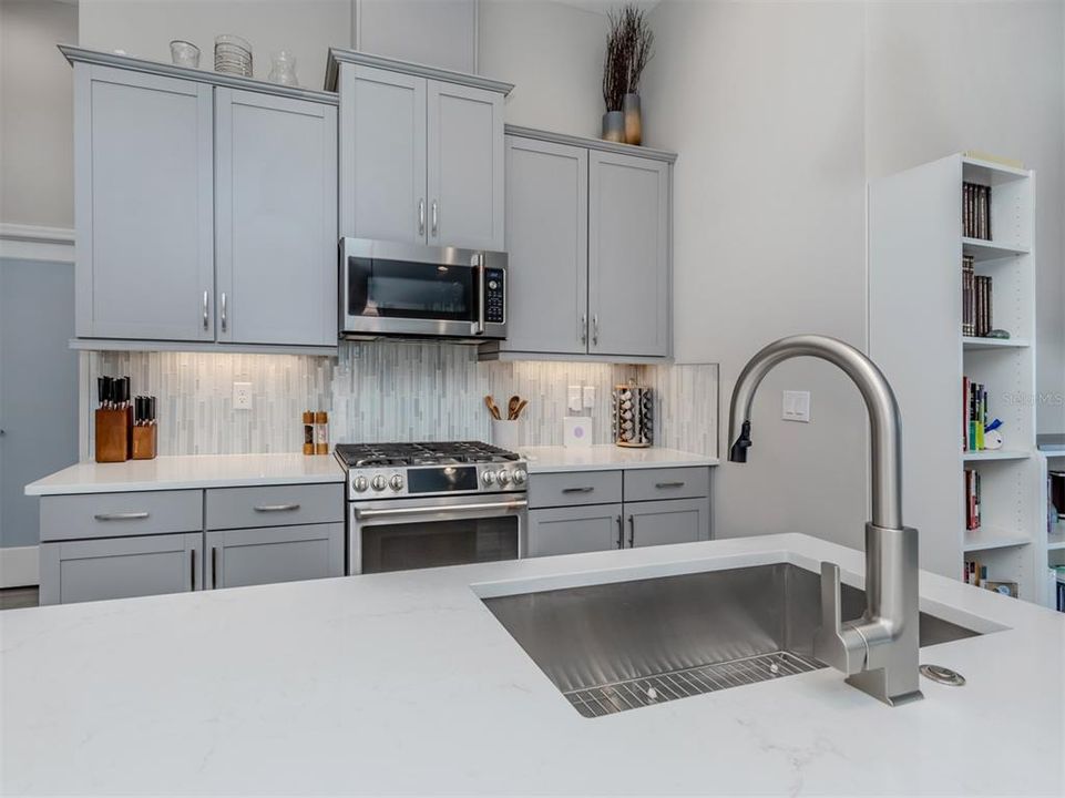 The custom backsplash, large walk-in pantry with frosted door, and farm sink completes this beautiful kitchen