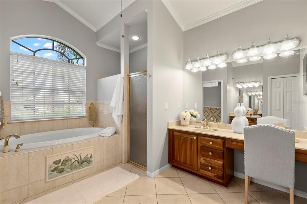 Primary ensuite bathroom with his and her walk-in closets, soaking tub, stand up shower, water closet, his and her vanity, decorative tile, and linen closet.