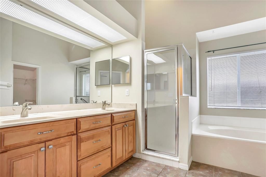 Primary bathroom with dual sinks, custom cabinets, shower and garden tub.