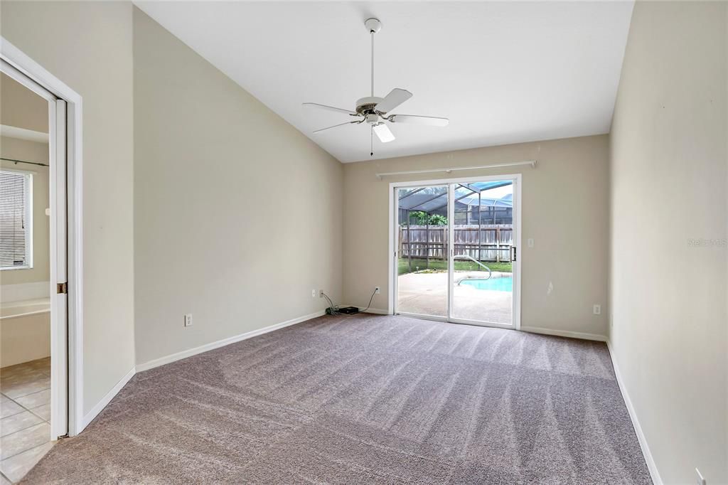 Primary bedroom with pool access and new carpet.