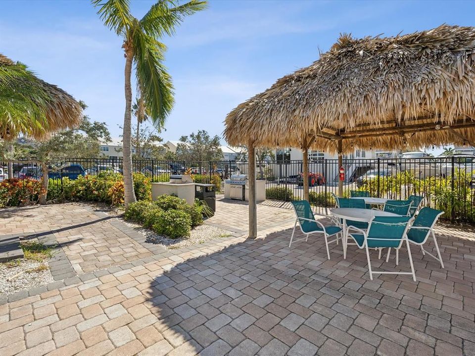 Pool area has tiki huts and gas grill