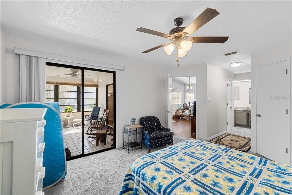 The larger bedroom suite, a.k.a. Owner's Oasis, looking southward towards the Sun Room, with a peek into both the Living Room and the ensuite bath. Notice all the ceiling fans in this home? They're everywhere - we love it!