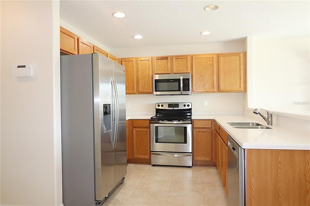 Kitchen is equipped with Corian countertops and wood cabinets