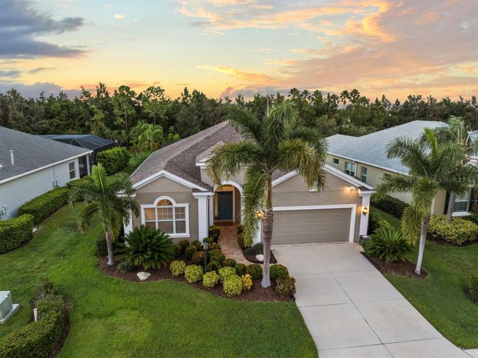 Front Elevation featuring tropical landscaping, custom lighting, and stunning elevation accents.