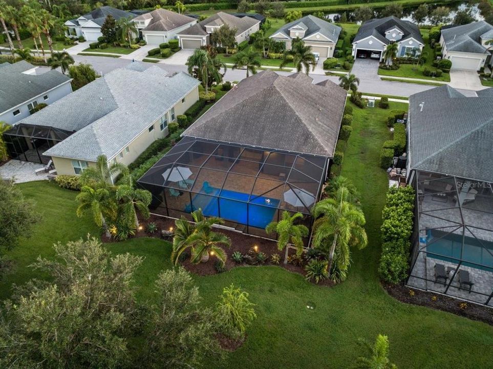 Aerial of the back side of the home showing the tropical landscaping and screened-in lanai.