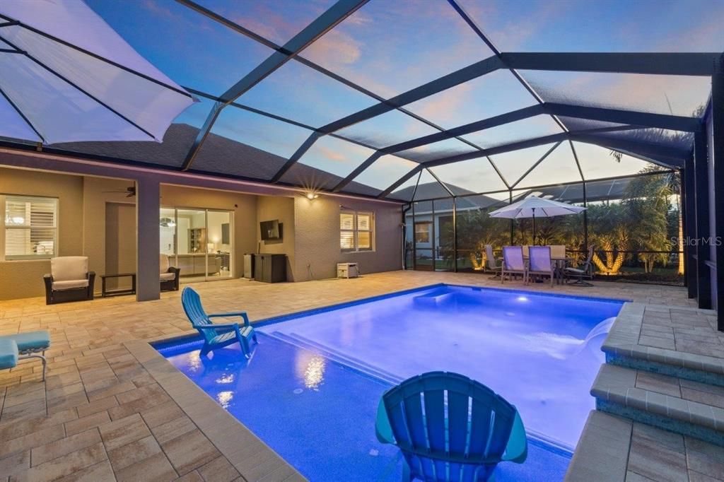 Huge screened-in lanai featuring paver floors, a new 2022 heated self cleaning pool, and a cover sitting area.