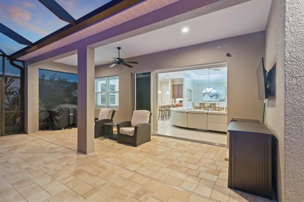 Huge screened-in lanai featuring paver floors, a new 2022 heated self cleaning pool, and a cover sitting area.