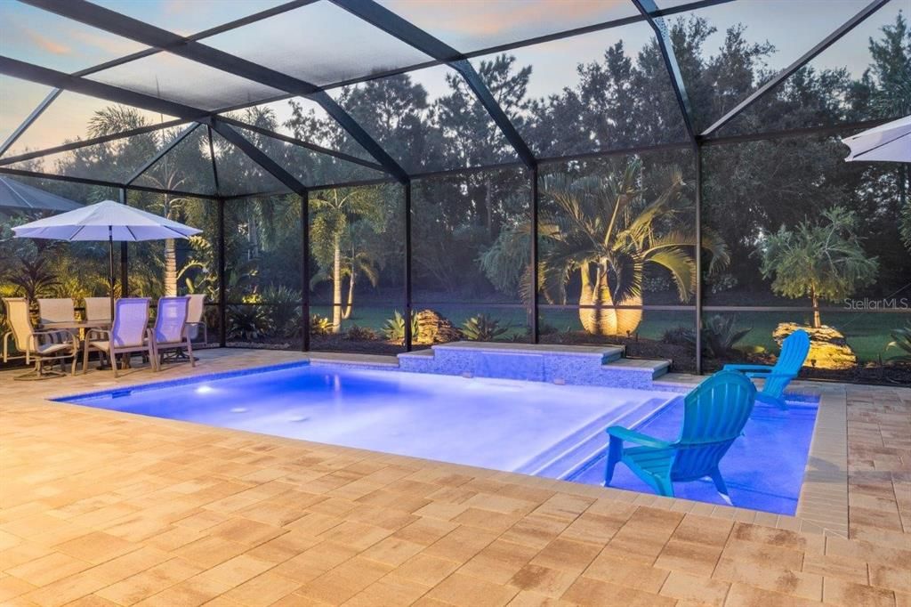 Huge screened-in lanai featuring paver floors, a new 2022 heated self cleaning pool, and a cover sitting area.