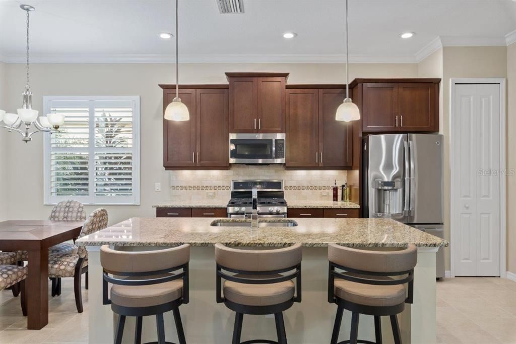 Stunning kitchen featuring granite countertops, stainless steel appliances, wood cabinets, and a dinette.