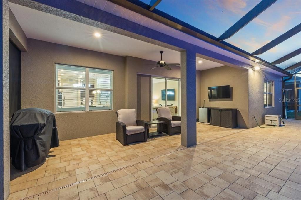 Huge screened-in lanai featuring paver floors, a new 2022 heated self cleaning pool, and a cover sitting area.