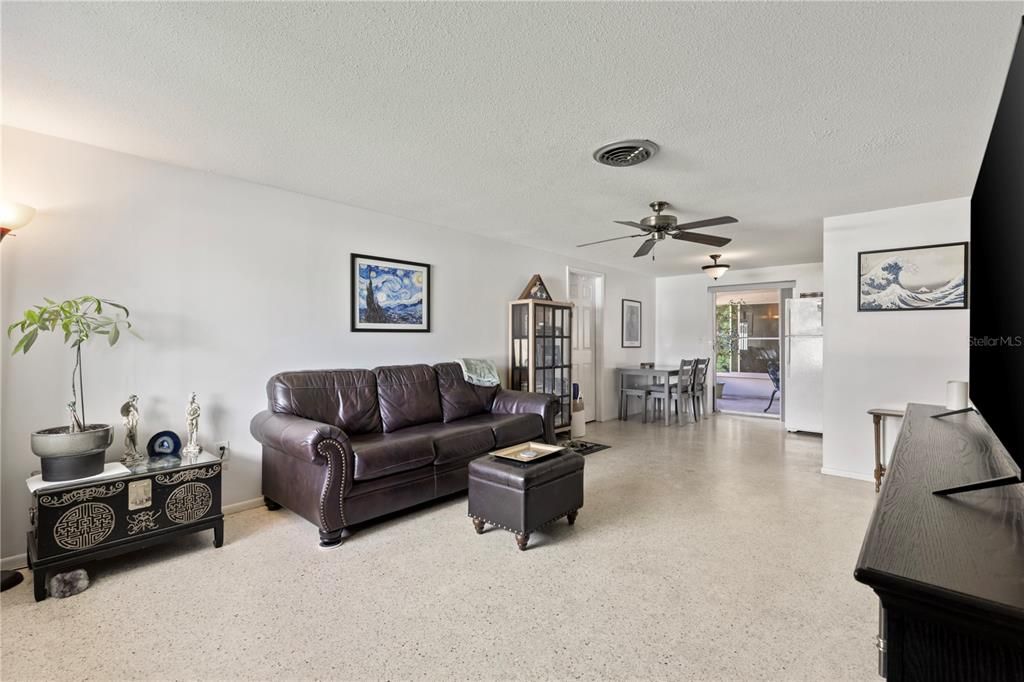 Living room featuring terrazzo floors, and large windows.