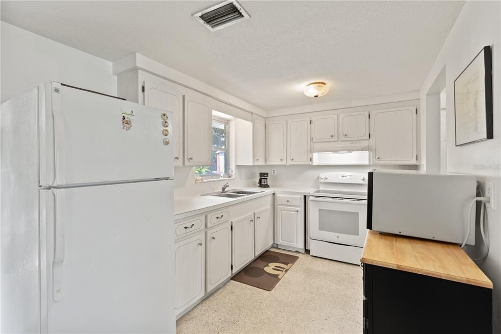 Galley style kitchen featuring ample cabinets, solid surface counter tops, and a garden window.