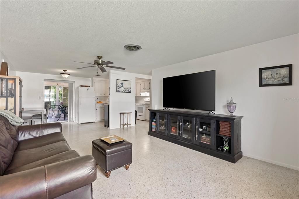 Living room featuring terrazzo floors, and large windows.