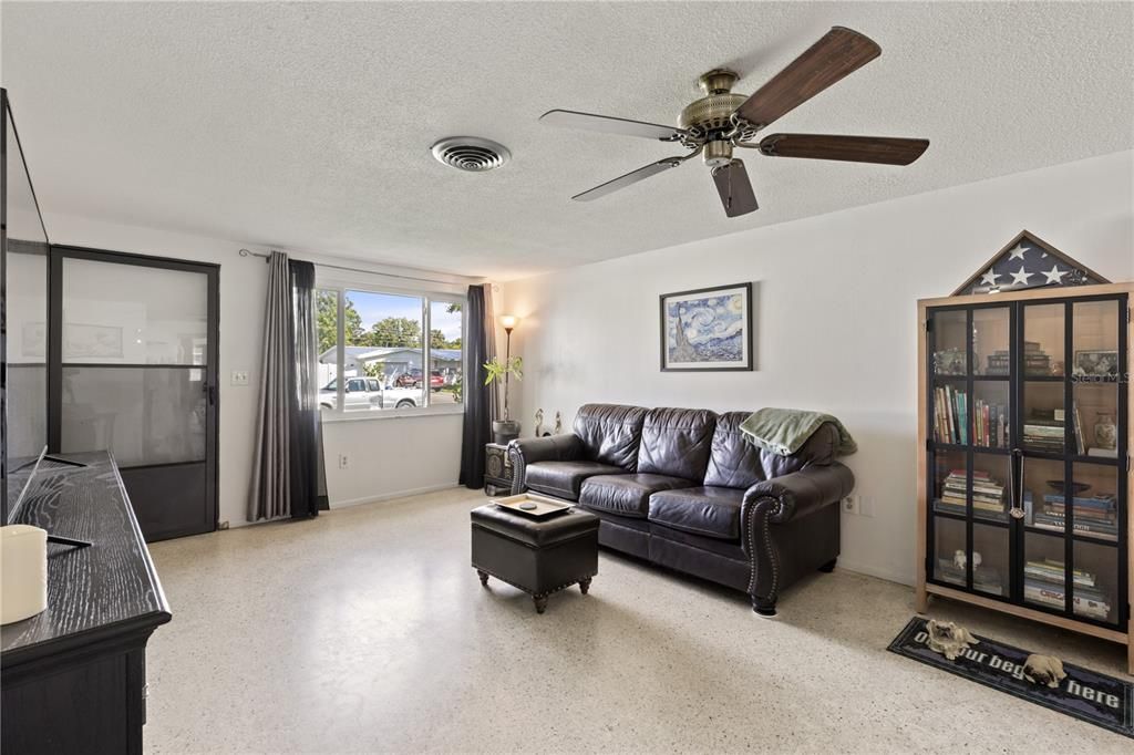 Living room featuring terrazzo floors, and large windows.