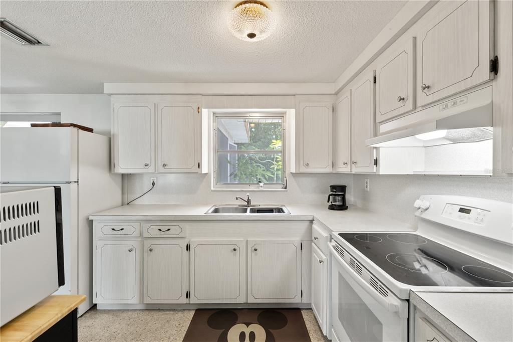 Galley style kitchen featuring ample cabinets, solid surface counter tops, and a garden window.