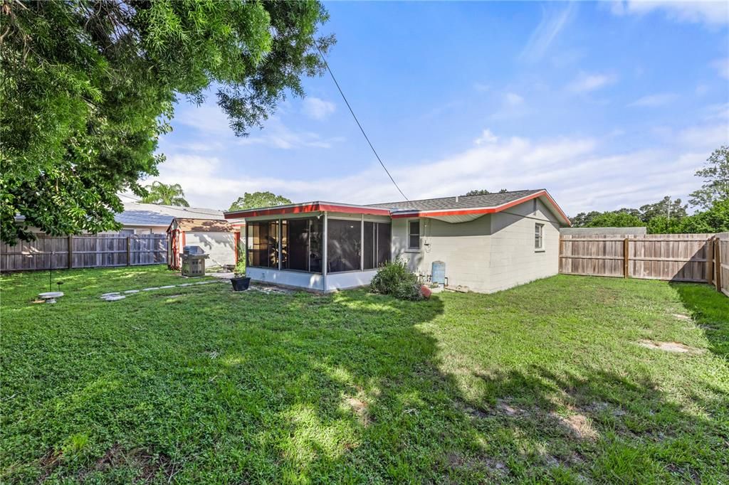 Spacious fully fenced-in back yard featuring a shed for extra storage.